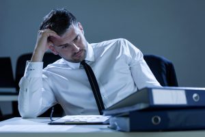 businessman at office table with hand on his head