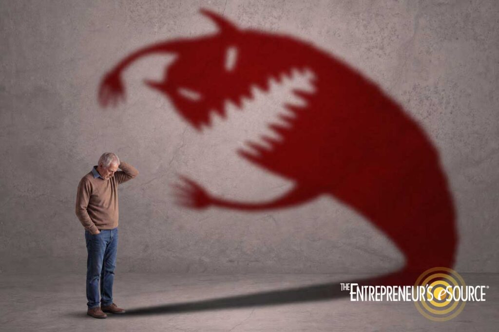 Older man stands with hand on head as a large red dragon shadow looms over him on the wall, with The Entrepreneur's Source logo in the corner.