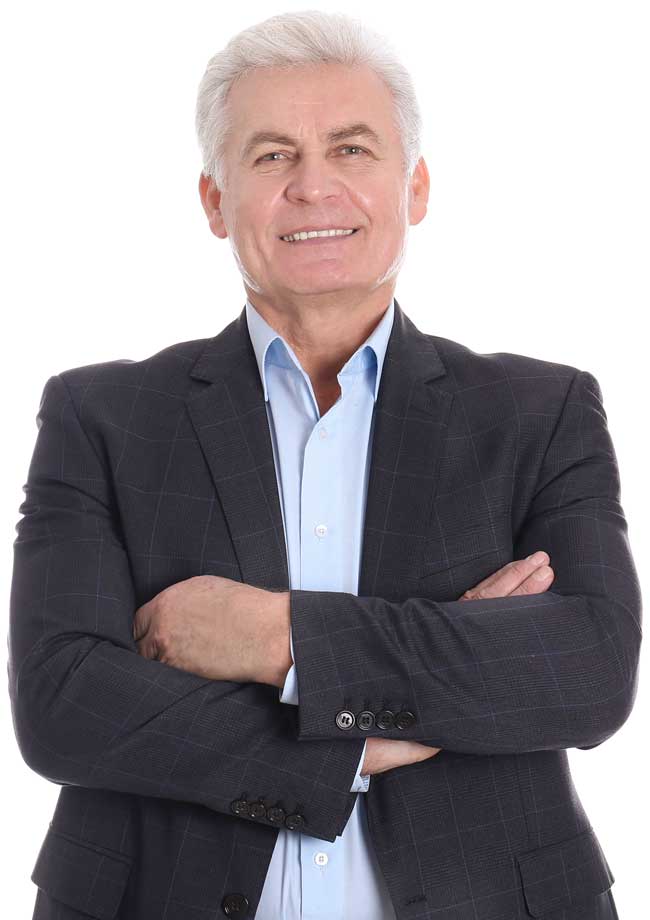 Professional portrait of a senior man with silver hair in a dark blazer and light blue shirt, arms crossed and smiling.