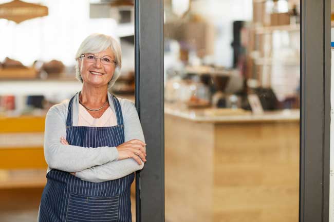 smiling-woman-in-apron-standing-in-storefront