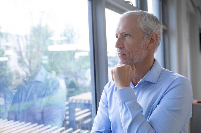 thoughtful-man-gazing-out-of-office-window